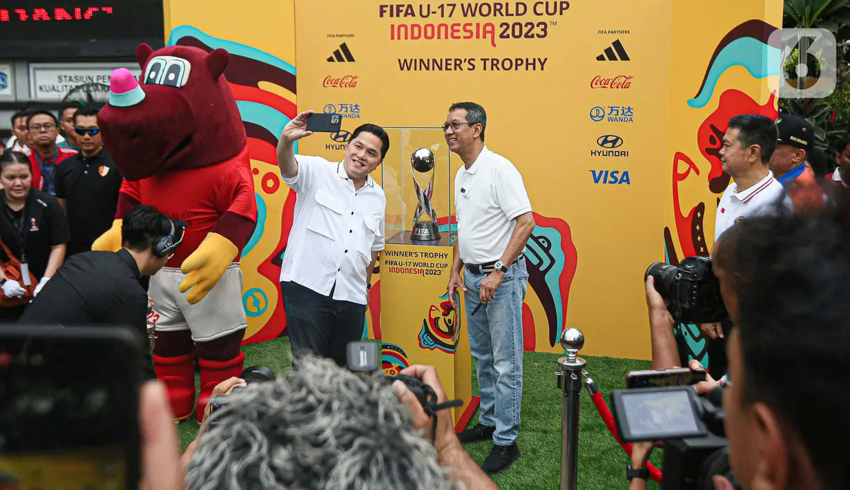 Menteri BUMN yang juga Ketua Umum PSSI Erick Thohir (tengah kiri) bersama Penjabat (Pj) Gubernur DKI Jakarta Heru Budi Hartono (tengah kanan) berswafoto bersama trofi Piala Dunia U-17 saat car free day (CFD) di kawasan Bundaran HI, Jakarta, Minggu (15/10/2023). Kegiatan tersebut dalam rangka promosi ajang Piala Dunia U-17 2023 di Indonesia. (Liputan6.com/Faizal Fanani)