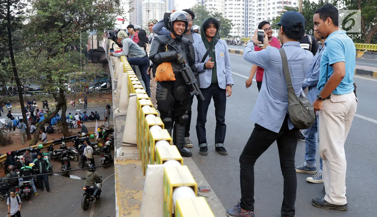 Mahasiswa dari salah satu perguruan tinggi berfoto dengan personel Brimob usai melakukan aksi unjuk rasa di sekitar Jembatan Layang Gerbang Pemuda, Jakarta, Selasa (1/10/2019). Mahasiswa dari berbagai perguruan tinggi kembali berunjuk rasa menolak beberapa RUU. (Liputan6.com/Helmi Fithriansyah)