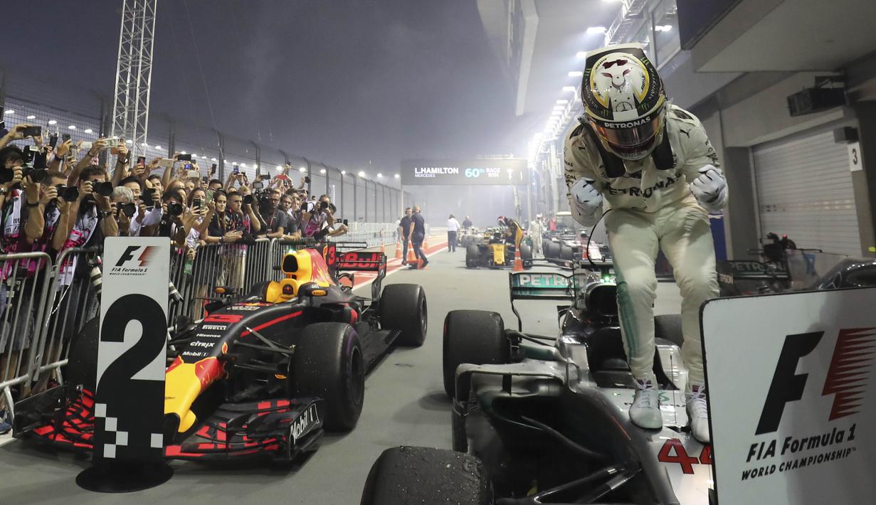 Ekspresi Lewis Hamilton saat berdiri di atas mobilnya usai menjuarai balapan F1 Singapura di Marina Bay City Circuit Singapore, (17/9/2017). (AP/Yong Teck Lim)