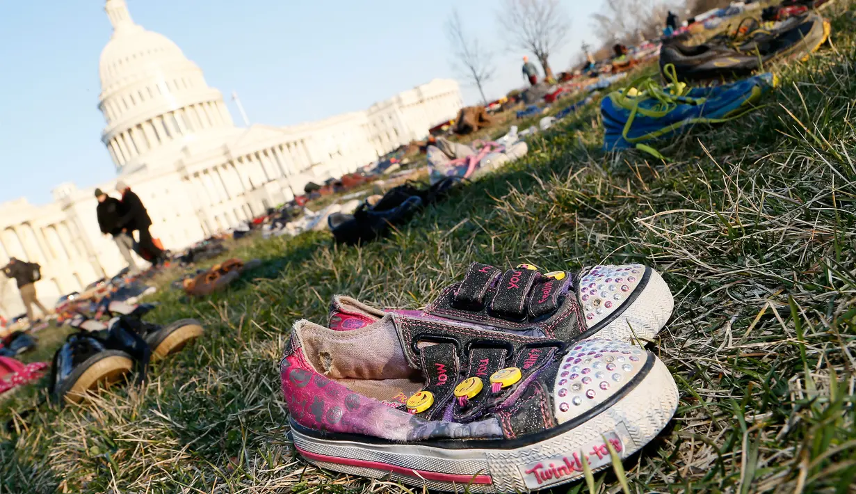 Ribuan sepatu menutupi halaman rumput di depan Gedung Capitol, Washington DC, Selasa (13/3). Sekitar 7000 ribu pasang sepatu dengan berbagai model diletakkan dan disusun secara trapesium. (Paul Morigi/AP Images for AVAAZ)