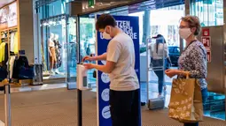 Para pelanggan membersihkan tangan sebelum memasuki sebuah toko di Berlin, Jerman (9/5/2020). Sementara peraturan kebersihan dan jaga jarak sosial (social distancing) minimum akan terus diberlakukan. (Xinhua/Binh Truong)