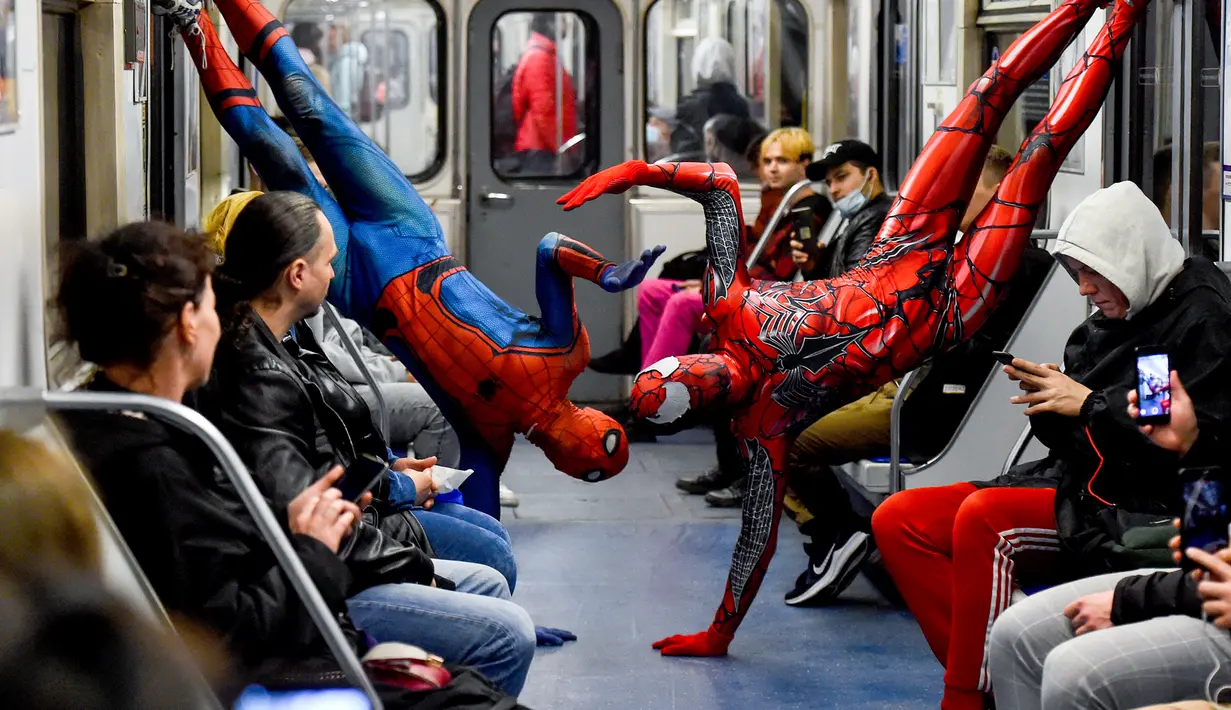 Penari underground yang mengenakan kostum Spiderman tampil di kereta bawah tanah Saint Petersburg, Rusia pada 21 Mei 2021. Penari berkostum Spiderman tersebut tampil berjungkir, melompat dan melakukan gerakan akrobatik di kabin kereta bawah tanah. (Olga MALTSEVA / AFP)