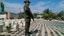 Seorang polisi Kolombia berdiri di antara 8 ton kokain dalam bentuk bungkusan paket yang disita di sepanjang wilayah perbatasan dengan Panama, Minggu (15/5). Menurut pejabat setempat, ini adalah penemuan terbesar di Kolombia. (Colombian Police/AFP)