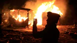 Imigran berdiri di depan tempat tinggalnya yang dibakar pihak berwenang di lahan kumuh yang dijuluki "Jungle" di Calais, Prancis (1/3). Pembakaran ini memunculkan protes bagi ribuan imigran yang tinggal di lokasi tersebut. (REUTERS/Pascal Rossignol)