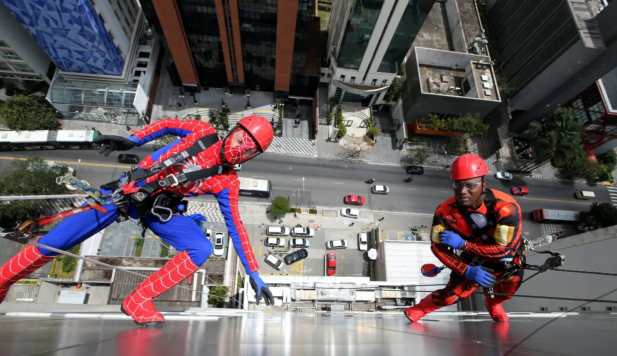 Dua petugas pembersih kaca berkostum Spiderman dan Iron Man bersiap menghibur pasien anak di RS Infantil Sabara, Sao Paulo, Senin (10/10). Aksi ini bagian dari perayaan Hari Anak Brasil yang diperingati tiap 12 Oktober. (REUTERS/Paulo Whitaker)