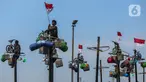 Peserta mengikuti perlombaan panjat pinang di pantai Ancol, Jakarta, Sabtu (17/8/2024). (Liputan6.com/Angga Yuniar)