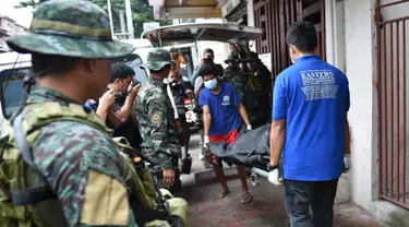 Personel polisi Filipina mengamati pekerja yang membawa jasad seorang napi yang tewas akibat kerusuhan di sebuah penjara di Filipina, Rabu (28/9). Selain menewaskan satu anggota geng narkoba, kerusuhan itu juga melukai tiga napi lainnya. (TED Aljibe/AFP)