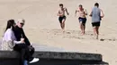 Warga bersantai dan berolahraga di sebuah pantai di Melbourne, Australia, Kamis (19/8/2021). Melbourne melewati 200 hari dalam lockdown keras sejak dimulainya pandemi COVID-19. (William WEST/AFP)