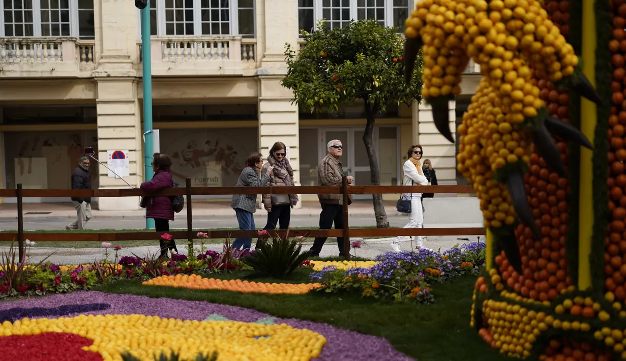Turis melihat patung yang dibuat dengan lemon dan jeruk selama Festival Lemon ke-88 di Menton, Prancis selatan, Sabtu (19/2/2022). Festival ini berlangsung pada 12-27 Februari dengan tema "Opera dan Tarian". (AP Photo/Daniel Cole)