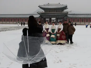 Pengunjung foto bersama saat salju turun di Istana Gyeongbok di Seoul, Korea Selatan (15/2). Istana Gyeongbok merupakan kerajaan utama selama Dinasti Joseon dan salah satu landmark terkenal di kota tersebut. (AFP Photo/Lee Jin-man)