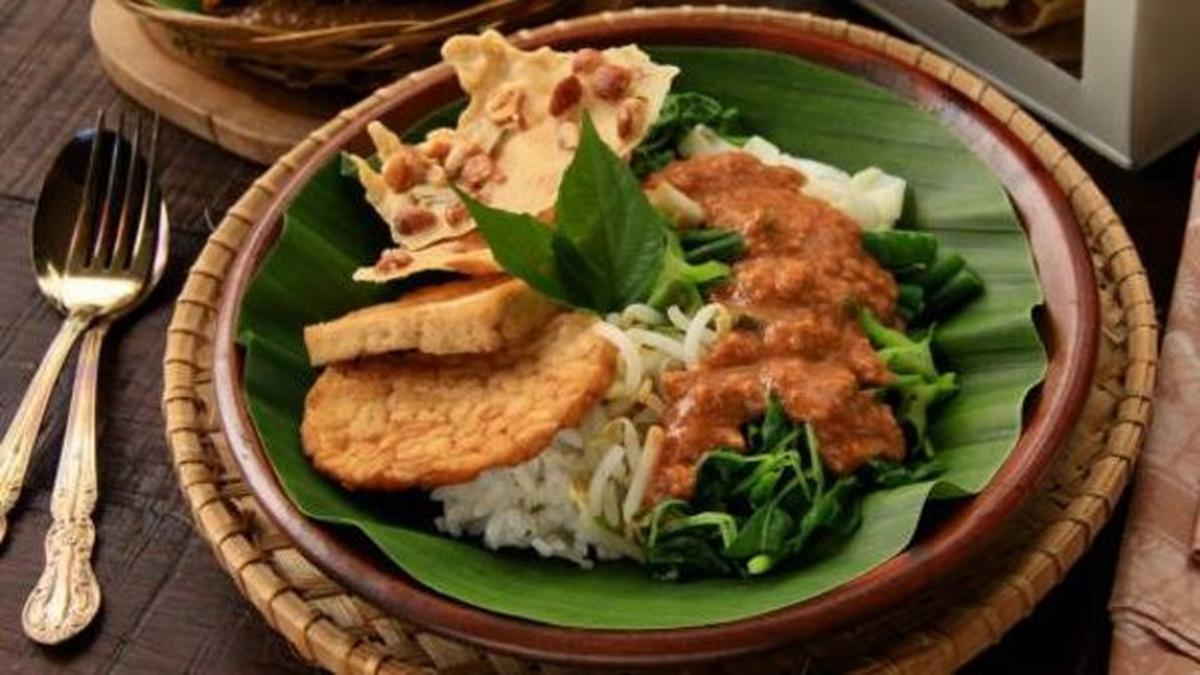 Sepiring lempeng pecel khas Jawa, lengkap dengan bumbu kacang gurih dan sayuran segar yang menggugah selera