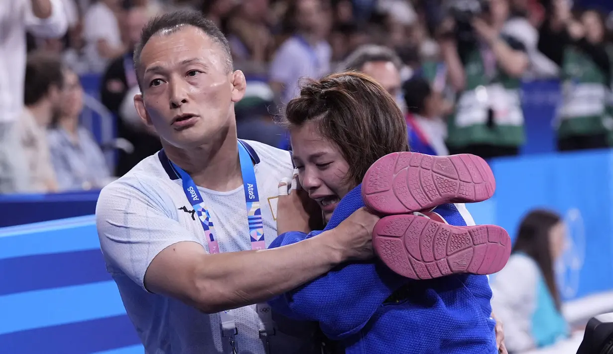 Pelatih berusaha menenangkan  Uta Abe yang menangis histeris. Abe merupakan juara dunia empat kali dan merupakan salah satu judoka favorit untuk memenangi medali emas. (AP Photo/Eugene Hoshiko)
