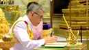 Raja Maha Vajiralongkorn menandatangani dokumen pernikahannya dengan Ratu Suthida saat melangsungkan prosesi pernikahan di Bangkok, Thailand, Rabu (1/5/2019). Raja Maha Vajiralongkorn yang kini berusia 66 tahun resmi menikahi Ratu Suthida yang berusia 40 tahun. (Thai TV Pool via Reuters)