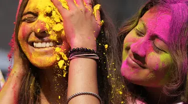 Orang yang bersuka ria mengolesi bedak berwarna di wajah orang lain selama perayaan menandai Holi, festival warna Hindu, di Mumbai, India (18/3/2022).  Holi, festival warna Hindu, juga menandai datangnya musim semi. (AP Photo/Rajanish Kakade)