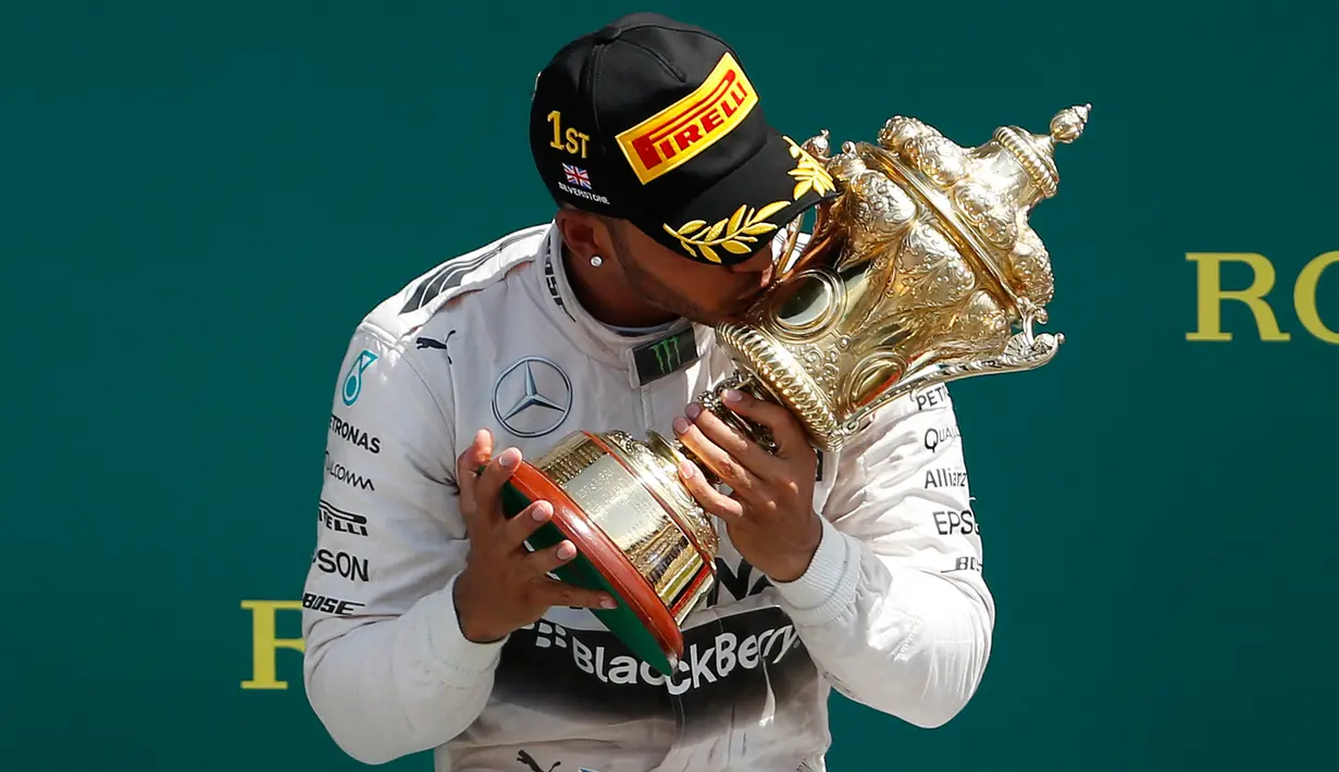 Pembalap Formula 1 tim Mercedes, Lewis Hamilton mencium piala yang diraihnya usai menjuarai Grand Prix Formula 1 Silverstone di Inggris, (5/7/2015). Hamilton berhasil finish di urutan pertama dengan waktu 1 jam 31 menit 27,729 detik. (Reuters/Phil Noble)