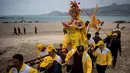 Penduduk desa menggunakan tandu membawa seorang pria berpakaian seperti Dewa Laut menuju pantai desa Fuye, Provinsi Fujian, Tiongkok (5/3). Mereka adalah komunitas nelayan setempat yang menggelar ritual kepercayaan. (AFP Photo/Johannes Eisele)