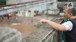 Warga mengamati banjir yang menggenangi kawasan Rawajati dari atas flyover di Jakarta Timur, Rabu (1/1/2020). Banjir yang berasal dari luapan Sungai Ciliwung itu menjadi daya tarik tersendiri bagi sebagian pemotor yang melintasi di flyover tersebut. (Liputan6.com/Immanuel Antonius)