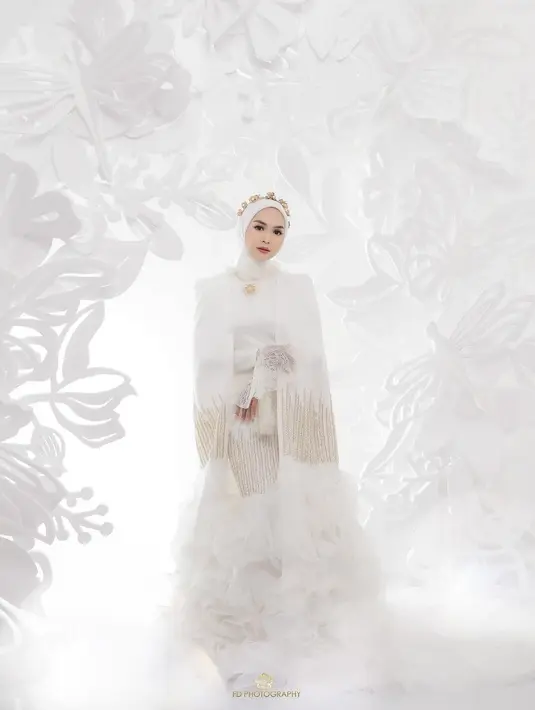 Ia mengenakan gaun panjang putih dengan bawahan ruffle tulle dan aksen garis berpayet gold. [@fdphotography90]