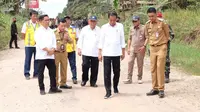 Presiden Jokowi dan sejumlah pejabat saat meninjau jalan produksi nanas yang rusak parah di Desa Tangkit, Kecamatan Sungai Gelam, Muaro Jambi, Selasa (16/5/2023). Pemerintah pusat mengambil alih perbaikan jalan produksi nanas di desa itu. (Liputan6.com/Pemkab Muaro Jambi)
