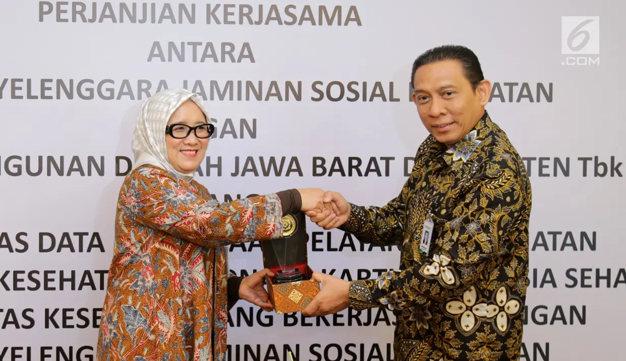 Direktur Komersial PT Bank BJB, Tbk Suartini (kiri) dan Direktur Keuangan dan Investasi BPJS Kesehatan Kemal Imam Santoso (kanan) bertukar cinderamata usai penandatanganan kerjasama, Jakarta, Rabu (22/11). (Liputan6.com/Angga Yuniar)