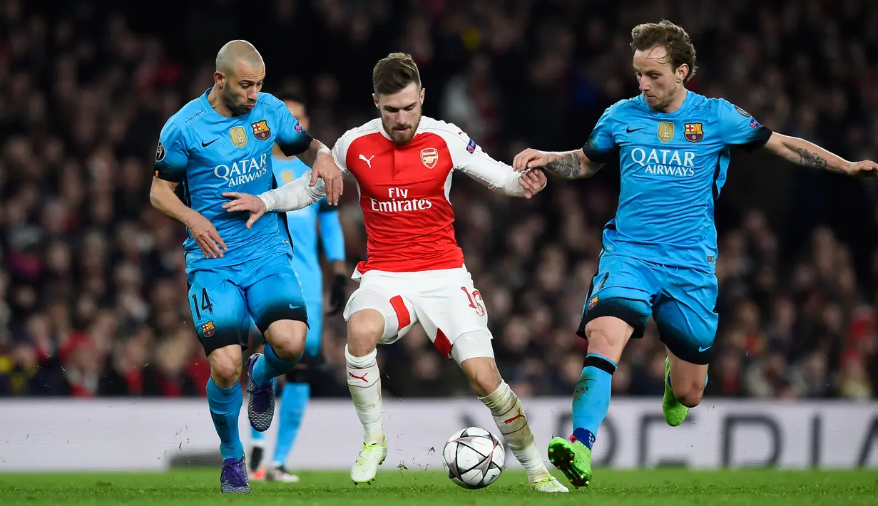 Aaron Ramsey berusaha melewati dua gelandang tangguh Barcelona, Javier Mascherano dan ivan rakitic pada leg pertama 16 besar Liga Champions di Stadion Emirates, Inggris (24/2). Barcelona menang atas Arsenal dengan skor 2-0. (Reuters/Dylan Martinez)