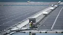 Petugas memeriksa panel surya fotovoltaik mengapung di kompleks pembangkit listrik O'Mega1 di Piolenc, Prancis selatan (30/7/2019). Pembangkit listrik tenaga surya (PLTS) mengapung pertama di Eropa ini akan beroperasi pada September 2019. (AFP Photo/Gerard Julien)