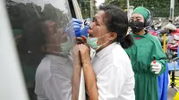 Seorang wanita bereaksi ketika petugas kesehatan mengambil sampel usap hidung darinya saat tes publik untuk virus corona COVID-19 yang dilakukan di stasiun kereta api di Bekasi, Jawa Barat, Rabu (2/2/2022). (AP Photo/Achmad Ibrahim)