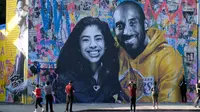 Orang-orang mengabadikan mural Kobe Bryant dan Putrinya Gigi buatan seniman Prancis Mr. Brainwash di Los Angeles (31/1/2020). Bryant memenangkan lima gelar juara NBA dan peraih medali emas Olimpiade dua kali. (AFP/Chris Delmas)