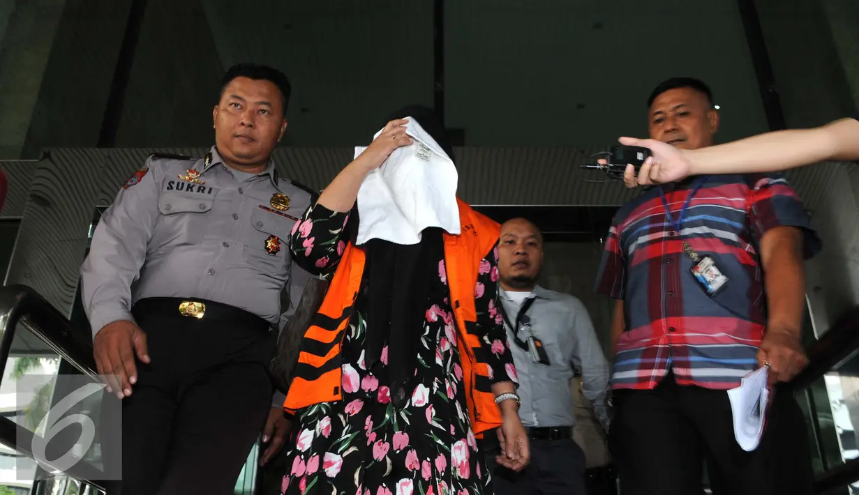 Komisaris CV Timur Alam Raya, Sri Astuti menutupi wajah usai menjalani pemeriksaan di KPK, Jakarta, Senin (22/8). Sri Astuti diduga melakukan penyuapan terkait pengadaan pupuk urea di PT Berdikari tahun anggaran 2010-2012. (Liputan6.com/Helmi Afandi)