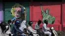 Seorang seniman melukis mural Marilyn Monroe, di samping salah satu Patung Liberty yang memakai masker untuk menyebarkan kesadaran akan pencegahan virus corona di Mumbai, India (26/3/2021). India telah melaporkan jumlah kasus virus corona tertinggi dalam empat bulan. (AP Photo/Rajanish Kakade)