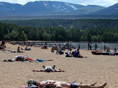 Orang-orang berjemur di pantai di Loch Morlich dekat Aviemore, di Skotlandia, (28/5). Cuaca panas tengah melanda sebagian besar wilayah di Inggris. (AP Photo/Jane Barlow)