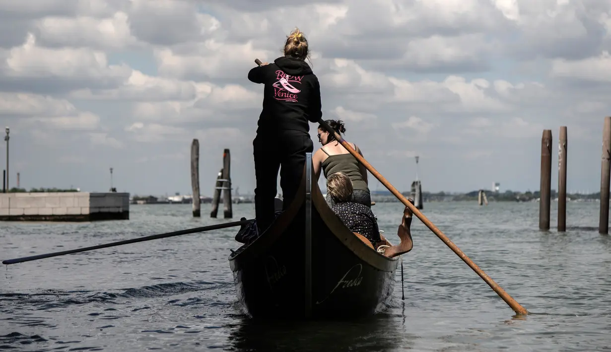 Perempuan yang tergabung dalam Row Venice menawarkan pengalaman belajar mendayung gondola di sebuah kanal di Venesia, Italia pada 16 Mei 2019. Pengalaman ini bisa dimiliki dengan sekitar Rp 1,37 juta per gondola selama 90 menit untuk empat orang yang dimulai pukul 10.00 pagi. (MARCO BERTORELLO/AFP)
