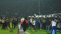 Polisi dan tentara pun akhirnya turun untuk mengamankan situasi. Kalah jumlah personil, mereka pun terlihat beberapa kali menembakkan gas air mata dalam kerusuhan suporter usai laga Arema Vs Persebaya di Stadion Kanjuruhan, Malang, Sabtu (1/10/2022) malam. (Bola.com/Iwan Setiawan)
