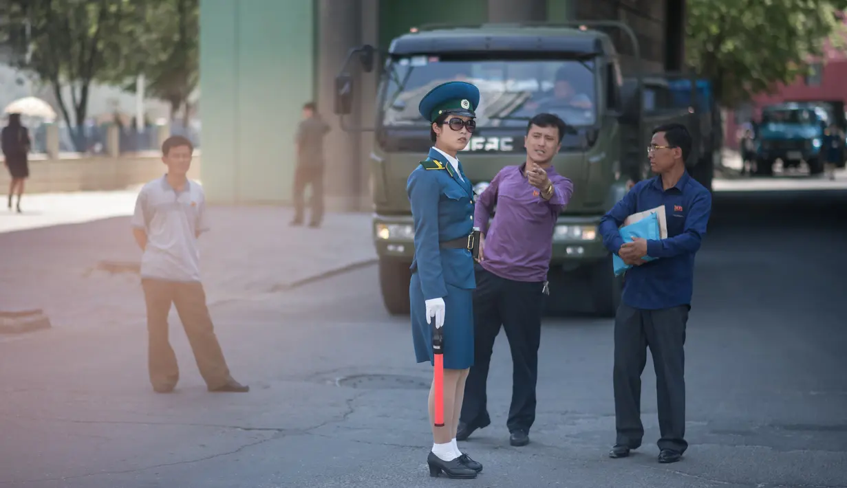 Seorang pejalan kaki berbicara dengan polisi wanita yang sedang mengatur lalu lintas di Pyongyang, Korea Utara (5/6). Polisi wanita pengatur lalu lintas ini juga menjadi daya tarik di kota Pyongyang. (AFP Photo/Ed Jones)