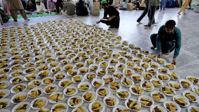 Relawan menata piring makanan untuk dibagikan kepada masyarakat saat berbuka puasa selama bulan suci Ramadhan, di Lahore, Pakistan, Selasa, 12 Maret 2024. (AP Photo/K.M. Chaudary)