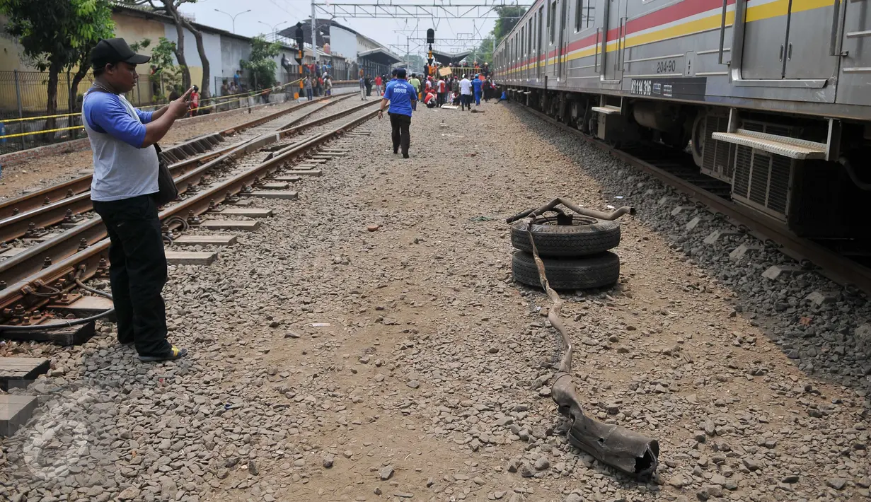 Petugas memotret bagian Metromini yang terlepas usai terjadi tabrakan dengan kereta di perlintasan Angke, Tambora, Jakarta, Minggu (6/12/2015). Sebanyak 13 orang dilaporkan tewas. (Liputan6.com/Gempur M Surya)  