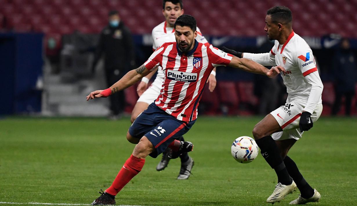 Striker Atletico Madrid, Luis Suarez, berusaha melewati pemain Sevilla, Fernando, pada laga Liga Spanyol di Stadion Wanda Metropolitano, Selasa (12/1/2021). Atletico Madrid menang dengan skor 2-0. (AFP/Pierre-Philippe Marcou)