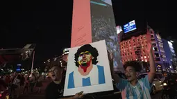 Seorang suporter memegang poster Diego Maradona untuk mendukung timnas Argentina sehari menjelang final Piala Dunia 2022, di Buenos Aires, Argentina, Sabtu, 17 Desember 2022. Argentina akan melawan Prancis pada babak final di Stadion Lusail Iconic, Minggu (18/12). (AP Photo/Rodrigo Abd )