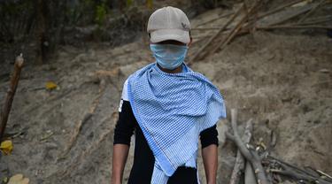 Polisi Myanmar yang membelot tampak memakai topi dan penutup wajah ketika difoto di lokasi yang dirahasiakan di negara bagian Mizoram, timur laut India (15/3/2021).  Ratusan polisi Myanmar bersama keluarganya telah melarikan diri ke India. (AFP/Sajjad Hussain)