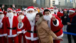 Seorang turis berfoto bersama dengan orang berpakaian seperti Santa Claus saat acara amal Natal di pusat kota Seoul, Korea Selatan, (24/12/2015). (REUTERS/Kim Hong-Ji)