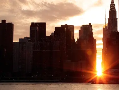 Pemandangan Manhattanhenge di New York, AS, Senin (11/7). Manhattanhenge adalah sebutan untuk sunset sempurna di New York di mana matahari berada tepat di antara 2 gedung yang terbelah dengan jalan. (Drew Angerer / Getty Images / AFP)
