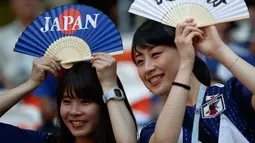 Dua suporter wanita tersenyum sambil memegang kipas sebelum pertandingan grup H Piala Dunia 2018 antara Jepang melawan Kolombia di Mordovia Arena di Saransk, Rusia (19/6). (AP Photo/Eugene Hoshiko)