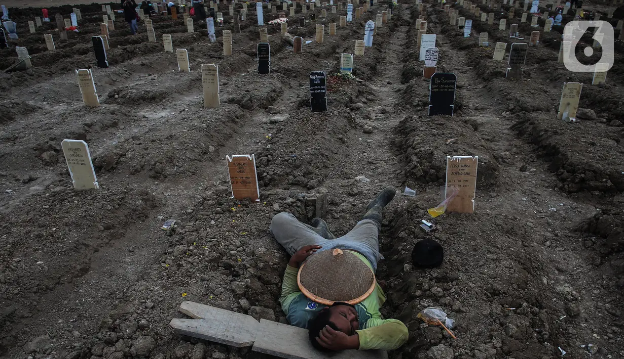 Petugas beristirahat di antara makam dengan protokol covid-19 di TPU Rorotan, Jakarta, Rabu (14/7/2021). Data untuk pasien meninggal per 14 Juli 2021 sebanyak 991 orang sehingga total akumulatif saat ini ada 69.210 orang yang meninggal dunia akibat corona di Indonesia. (Liputan6.com/Johan Tallo)