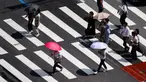 Pejalan kaki menggunakan payung saat menyeberangi jalan di Seoul pada tanggal 14 Agustus 2024. (Anthony WALLACE/AFP)