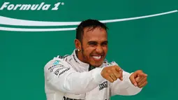 Pembalap Mercedes, Lewis Hamilton merayakan kemenangan usai merebut gelar Grand Prix F1 di Sirkuit The Americas, Minggu (25/10). Ini merupakan gelar juara dunia ketiga bagi Hamilton setelah sebelumnya diraih pada 2008 dan 2014. (REUTERS/Mike Stone)