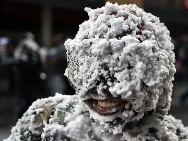 Warga bermain dengan busa, bedak, dan cat hitam selama Black Day atau Hari Hitam di Pasto, Kolombia, (5/1). Hari Hitam merupakan bagian dari karnaval orang kulit hitam dan kulit putih. (LUIS ROBAYO/AFP)