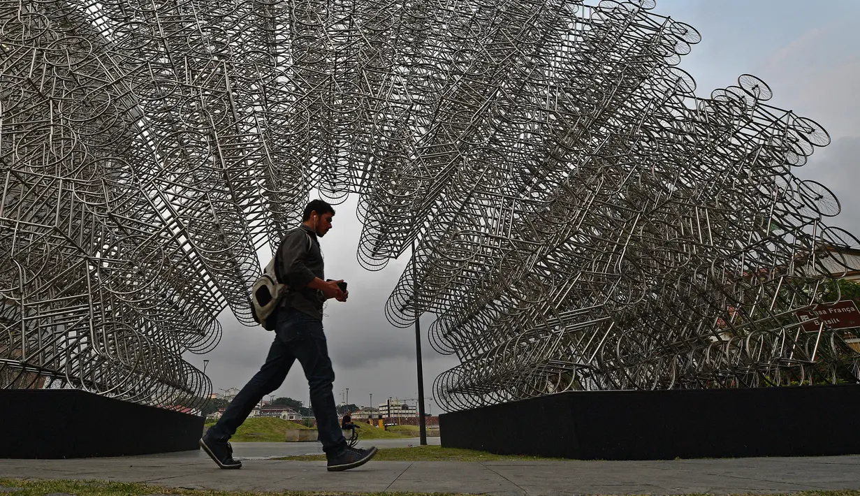 Seorang pejalan kaki melewati instalasi seni seniman China Ai Weiwei yang berjudul 'Forever Cycles' di Rio de Janeiro, Brasil, Senin (19/8/2019). Instalasi ini merupakan bagian dari pameran Ai Weiwei. (CARL DE SOUZA/AFP)