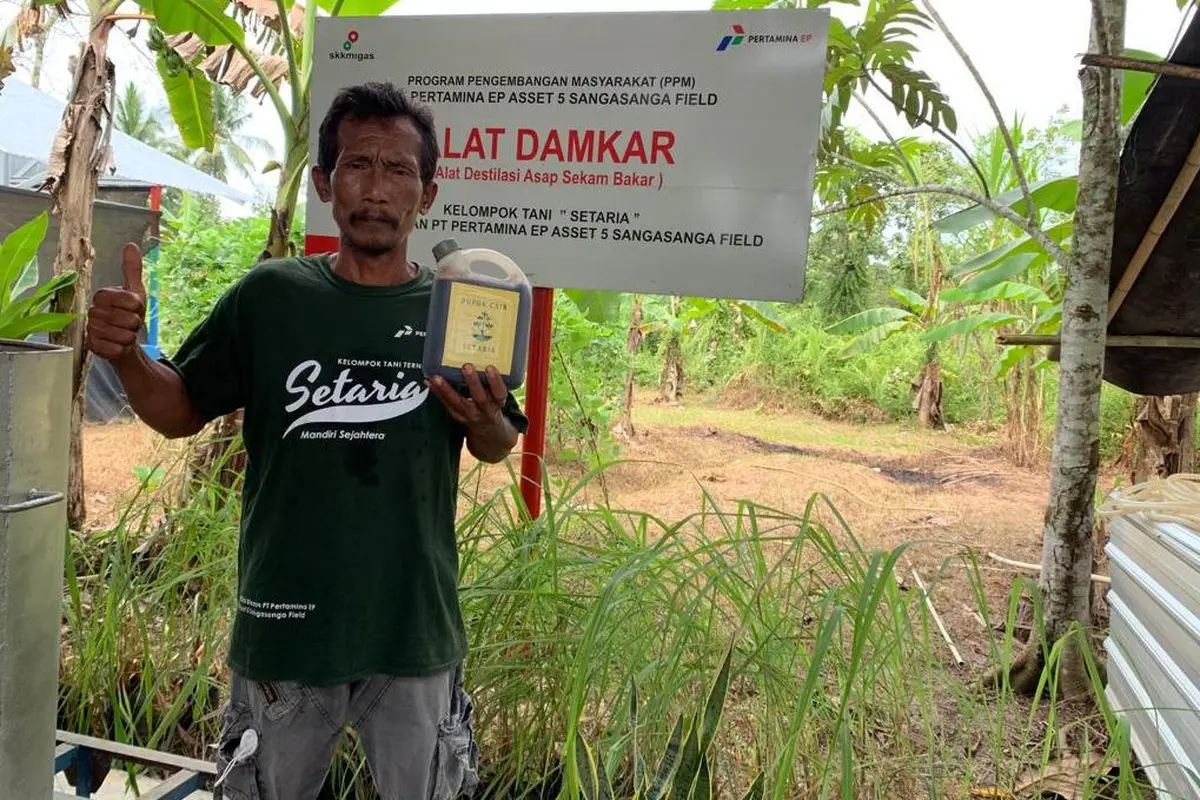 Sutrimo, Ketua Kelompok Setaria di Sangasanga, Kutai Kartanegara, Kalimantan Timur, memamerkan produk pupuk cair yang berasal dari inovasi DAMKAR, Alat Destilasi Asap Sekam Bakar.