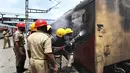 Petugas kereta api memadamkan api di gerbong kereta api di stasiun kereta api Secundrabad di Hyderabad, India, Jumat (17/6/2022). Hampir 500 pengunjuk rasa jauh melebihi jumlah polisi saat mereka mengamuk selama lebih dari satu jam di stasiun kereta api Secundrabad di India selatan. (AP Photo/Mahesh Kumar A)