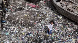 Seorang anak tengah berlari di tumpukan sampah yang mengering di dermaga Tempat Pelelangan Ikan Cilincing, Jakarta Utara, Rabu (8/2). (Fery Pradolo/Liputan6.com)